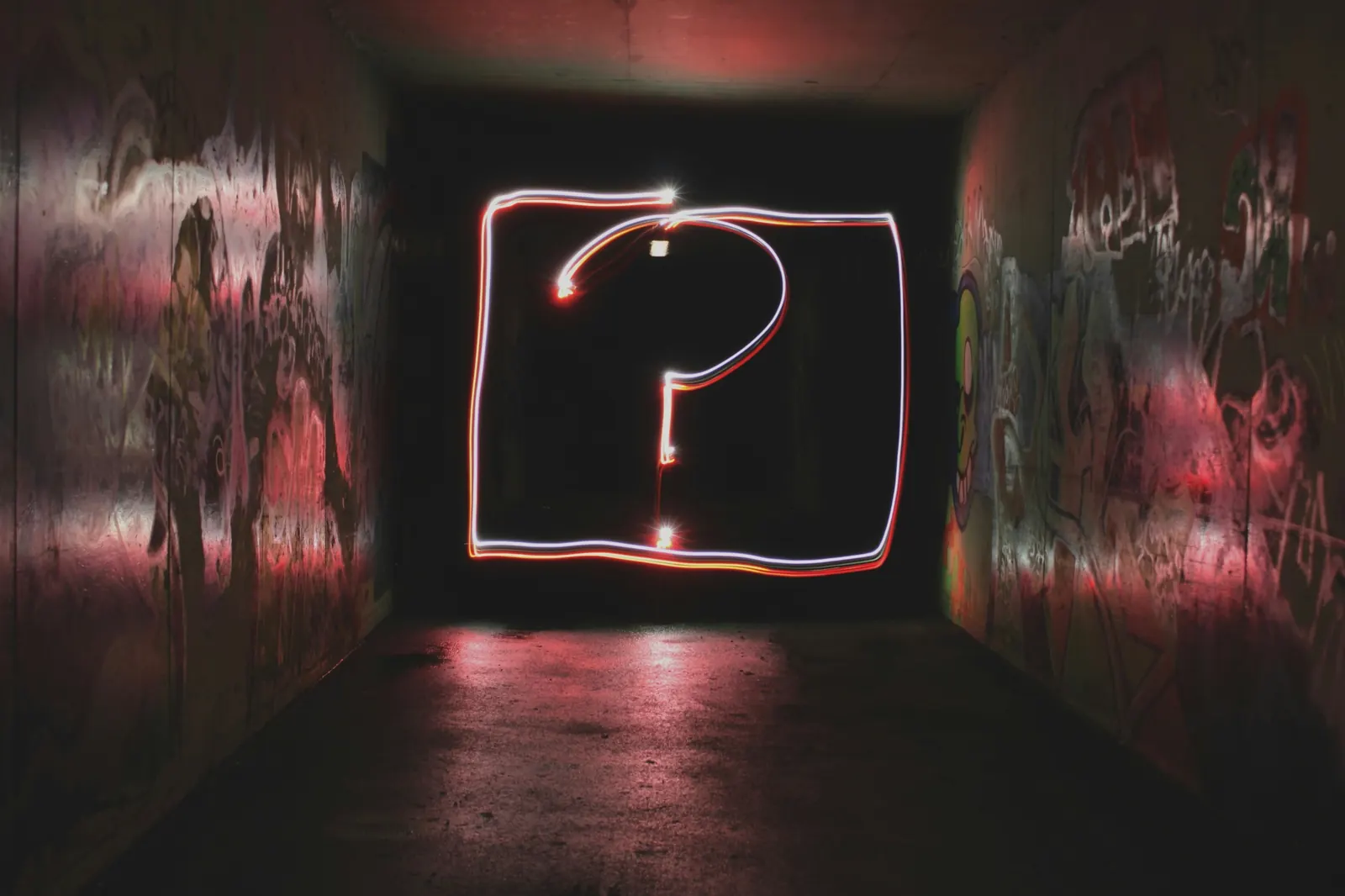 Un signo de interrogación de neón en una pared oscura